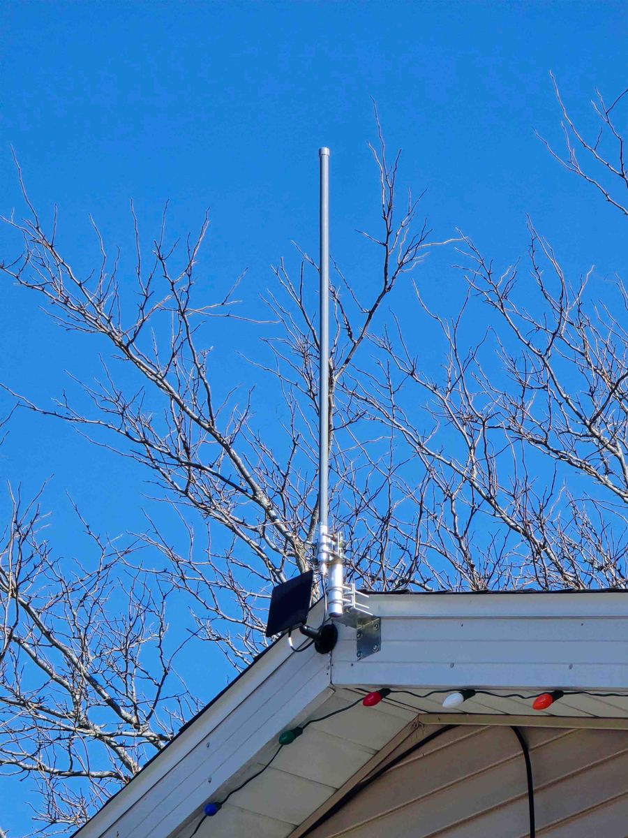 A mesh radio node mounted under a roof eave