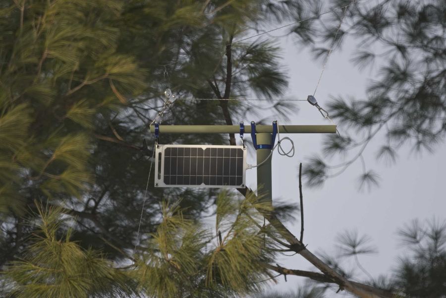 A weatherproof mesh radio node hanging outdoors